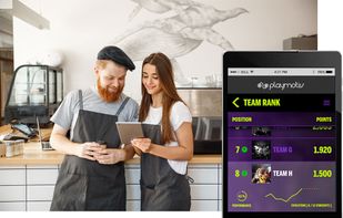 Image focused on the hospitality and horeca sector, where two professionals are using a tablet while a team ranking screen from the Playmotiv app is displayed. It represents the use of gamification to motivate teams, improve performance and track results in hospitality and restaurant environments